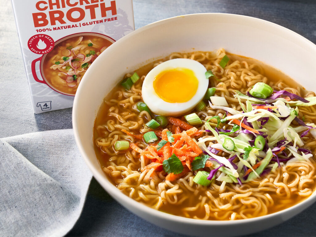 An image of prepared 15-Minute Spicy Chicken Ramen made with garlic, ginger, Swanson® Spicy Chicken Broth, ramen noodles, chicken, Asian slaw mix or broccoli slaw and hard cooked eggs.