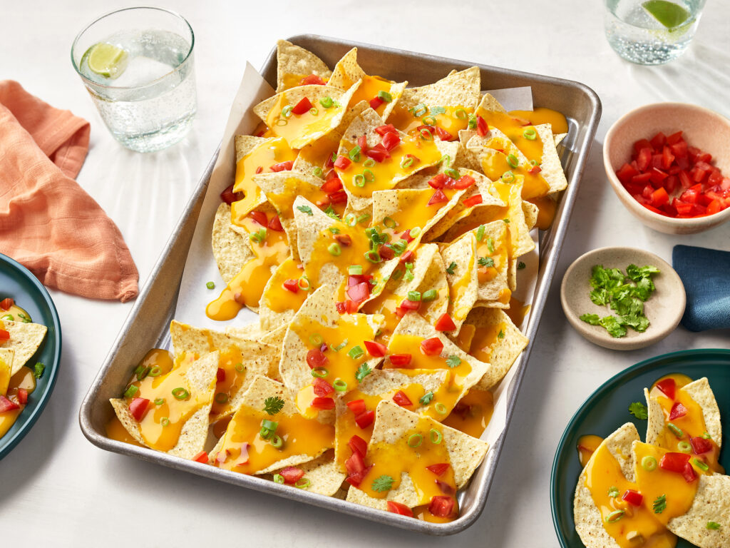 An image of prepared Super Quick Nachos made with tortilla chips, diced tomatoes, Campbell's® Condensed Spicy Nacho Cheese Soup and milk